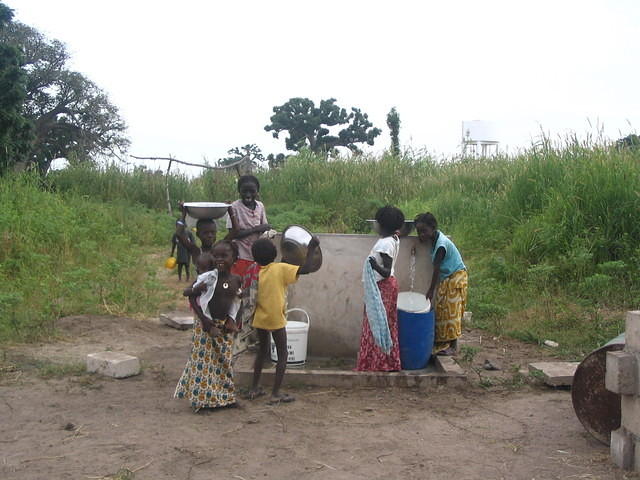 Groupe d'enfants remplissant seaux, marmites à la fontaine