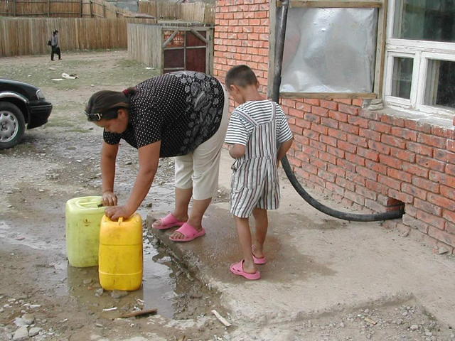 La responsable du kiosque à eau remplit des bidons d'eau.