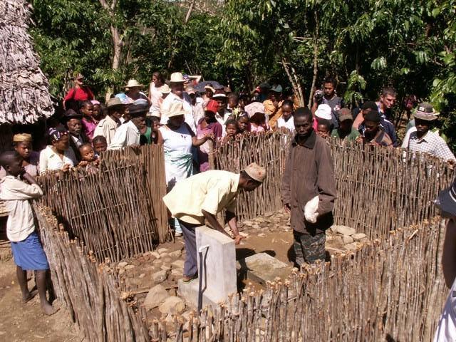 La population, autour de l'enclos, regarde les travaux de raccordement de la borne-fontaine