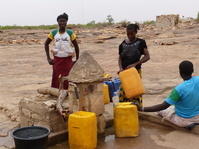 3 dames emplissent les bidons d'eau à la Borne fontaine - Commune de Sangha