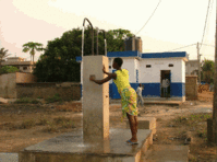 Borne-fontaine haute manoeuvrée par une dame; quartier de Nukafu; à l'arrière-plan, le bloc sanitaire.(©photo: ASDVT)
