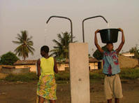 Les marmites d'eau d'une femme et d'un homme sont en cours de remplissage à la borne-fontaine haute
