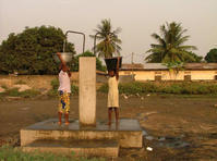 Les marmites d'eau de deux adolescentes sont en cours de remplissage à la borne-fontaine haute.
