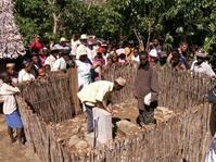 La population, autour de l'enclos, regarde les travaux de raccordement de la borne-fontaine